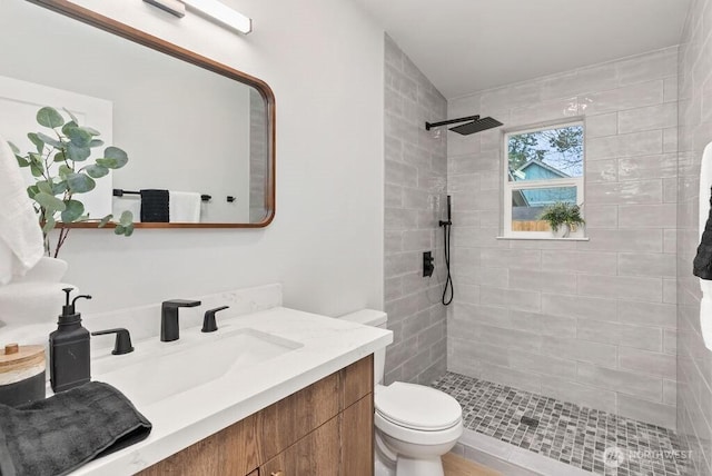 full bathroom featuring vanity, toilet, and tiled shower