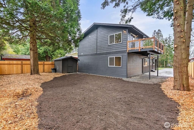 rear view of house with a deck, an outbuilding, fence, and a shed