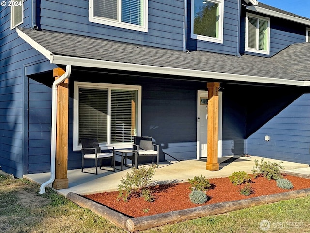 entrance to property with roof with shingles and a porch