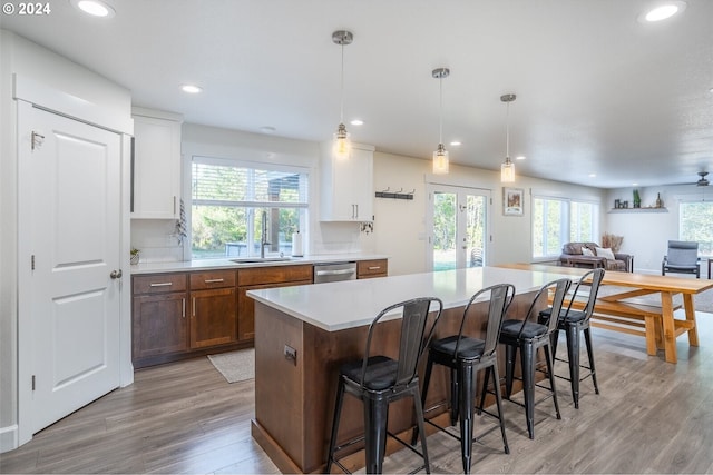 kitchen with a kitchen bar, a kitchen island, open floor plan, light wood-style floors, and dishwasher