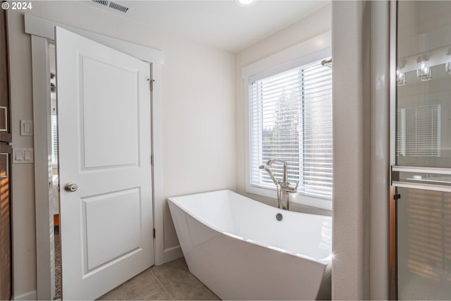 full bath with tile patterned floors, visible vents, and a soaking tub