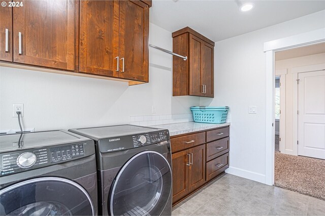 clothes washing area featuring cabinet space, washer and dryer, and baseboards