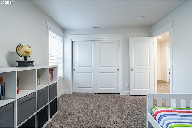 carpeted bedroom with visible vents, baseboards, and a closet