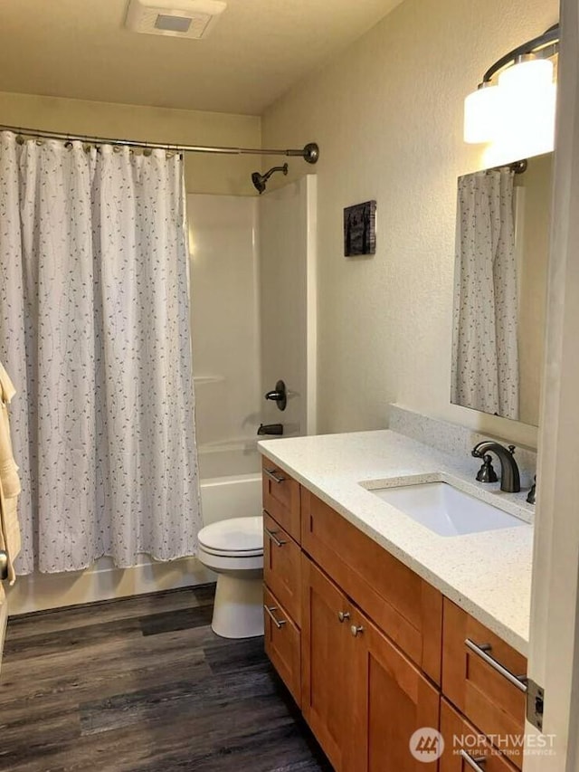 bathroom featuring visible vents, toilet, shower / bath combo with shower curtain, wood finished floors, and vanity