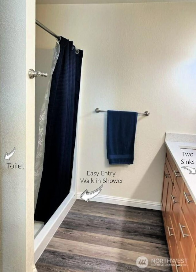 bathroom with a shower stall, vanity, baseboards, and wood finished floors