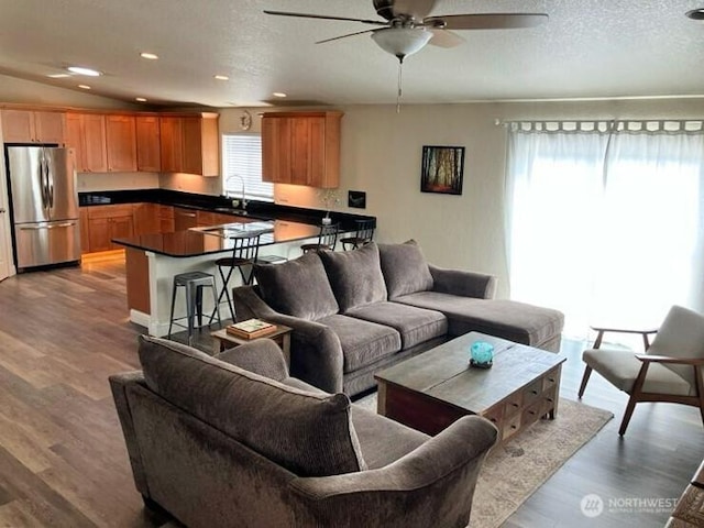 living area featuring a textured ceiling, wood finished floors, and ceiling fan