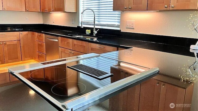 kitchen featuring dishwasher, dark countertops, range, and a sink