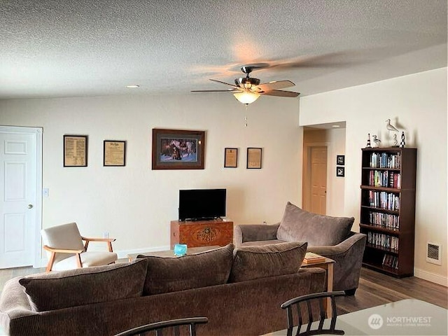 living area featuring a textured ceiling, dark wood-style floors, visible vents, and ceiling fan