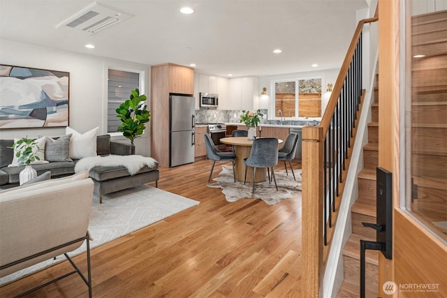 dining room with recessed lighting, light wood-style flooring, and stairs