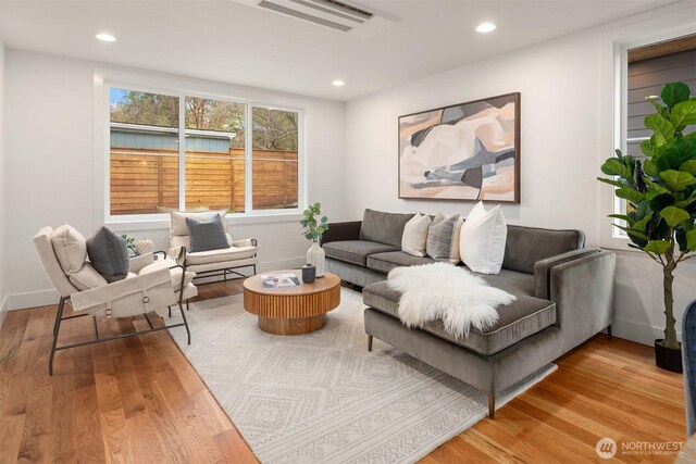 living room with recessed lighting, visible vents, baseboards, and wood finished floors