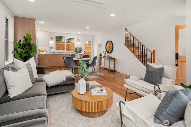 living area with stairs, light wood-style flooring, recessed lighting, and baseboards