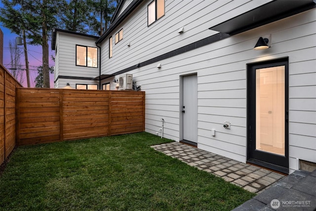 yard at dusk featuring a fenced backyard and ac unit