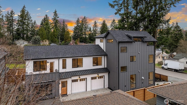 modern farmhouse featuring a garage, board and batten siding, driveway, and a shingled roof