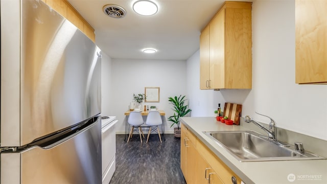 kitchen featuring visible vents, light brown cabinets, a sink, freestanding refrigerator, and light countertops