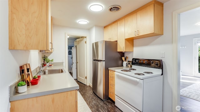 kitchen featuring visible vents, white range with electric cooktop, light brown cabinetry, freestanding refrigerator, and a sink