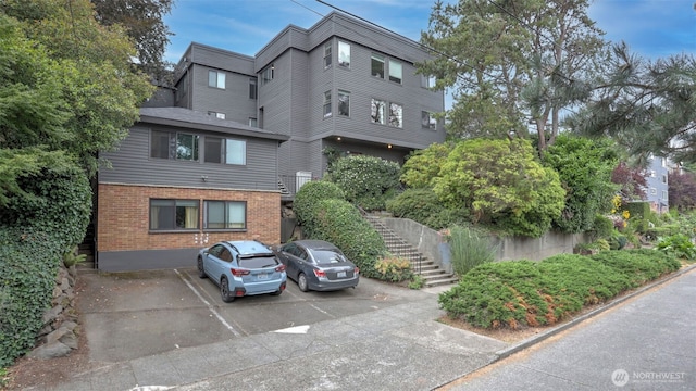 view of property featuring stairs and uncovered parking