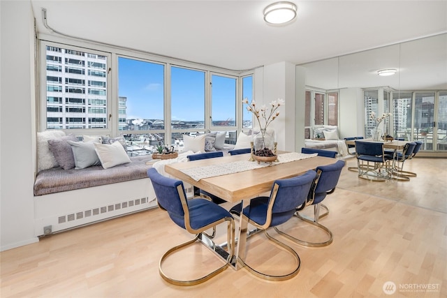 dining room featuring visible vents, a healthy amount of sunlight, wood finished floors, and floor to ceiling windows