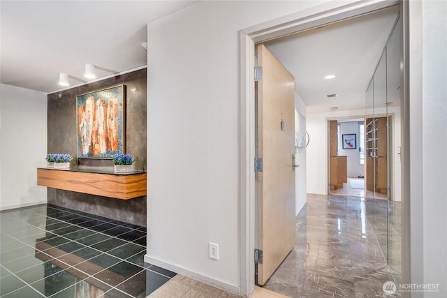 hall featuring visible vents, marble finish floor, and baseboards