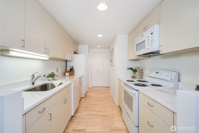 kitchen featuring recessed lighting, white appliances, light wood-style floors, and a sink