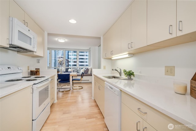 kitchen featuring a sink, white appliances, light wood-style flooring, and open floor plan