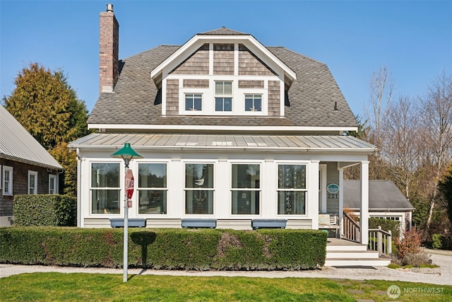 view of front of home with a shingled roof, a chimney, a standing seam roof, and metal roof