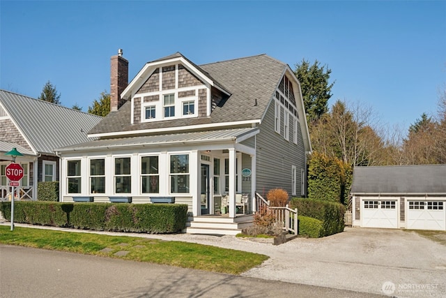 view of front facade featuring an outbuilding, a standing seam roof, roof with shingles, metal roof, and a chimney