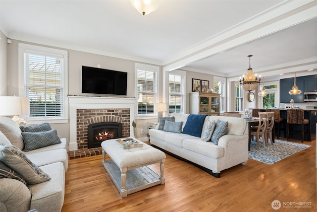 221 Meriweather St, Pacific Beach, WA 98571 - living area with crown molding, a notable chandelier, a fireplace, and light wood-type flooring