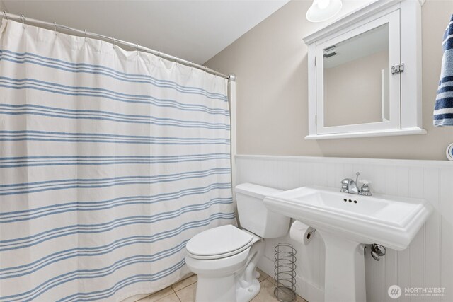 221 Meriweather St, Pacific Beach, WA 98571 - bathroom with a shower with shower curtain, a sink, wainscoting, tile patterned floors, and toilet