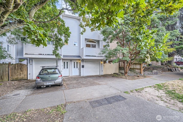 view of property with a gate, an attached garage, concrete driveway, and fence