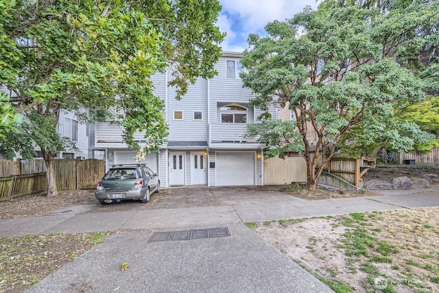 view of front of property with aphalt driveway, an attached garage, and fence