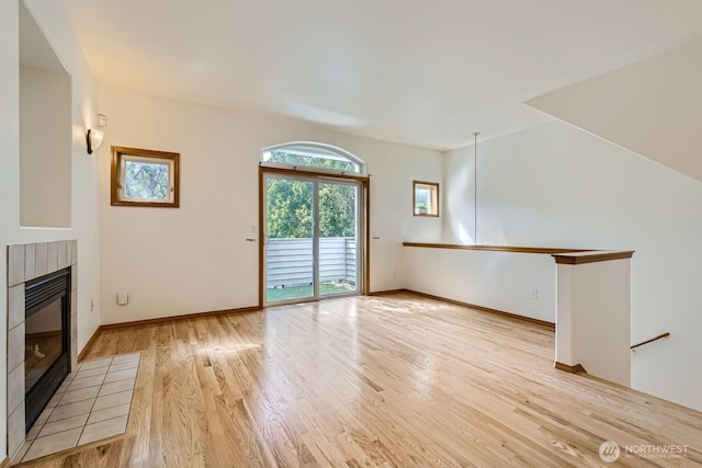 unfurnished living room with baseboards, light wood-style floors, and a fireplace