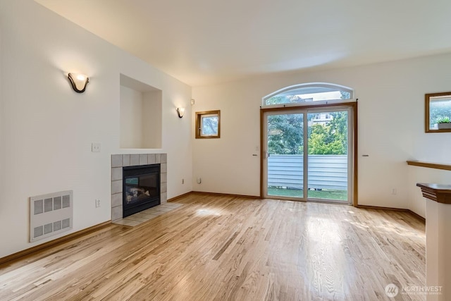 unfurnished living room with a fireplace, baseboards, and light wood finished floors