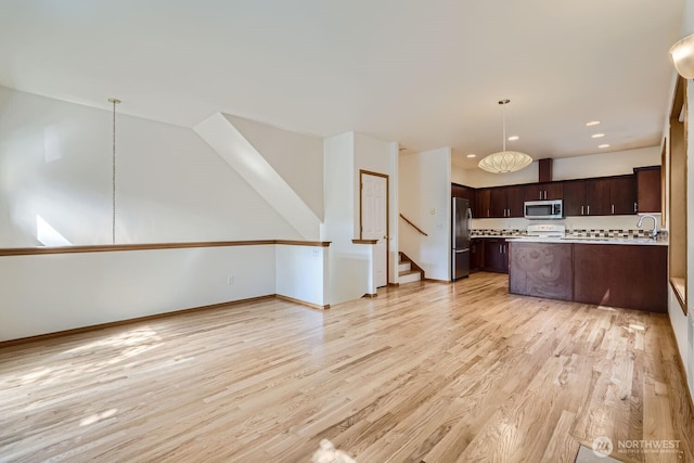 kitchen featuring open floor plan, dark brown cabinets, appliances with stainless steel finishes, and light wood-type flooring