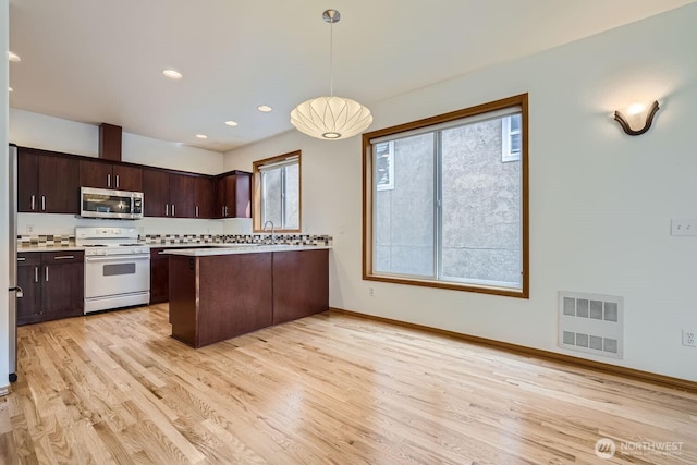 kitchen featuring visible vents, stainless steel microwave, dark brown cabinetry, light countertops, and white range with gas stovetop