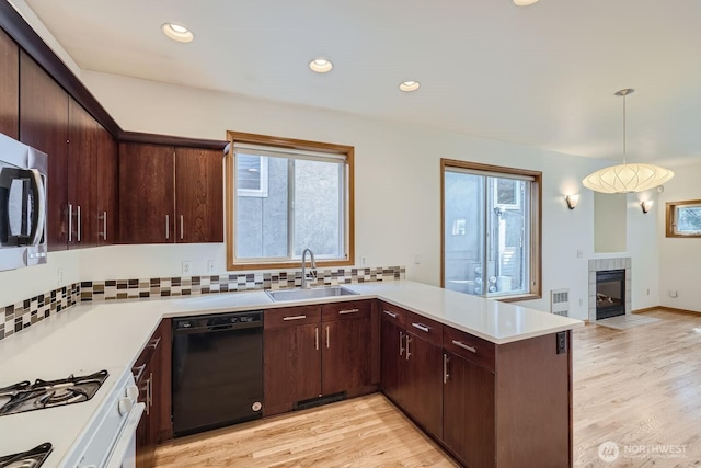 kitchen featuring visible vents, dishwasher, light countertops, a peninsula, and a sink