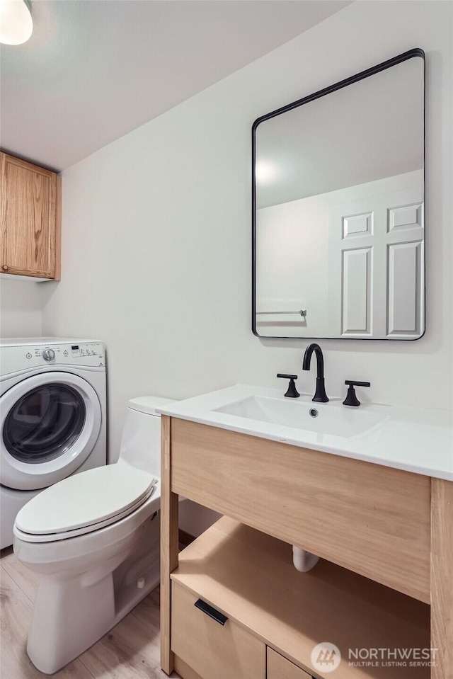 bathroom with toilet, washer / clothes dryer, vanity, and wood finished floors