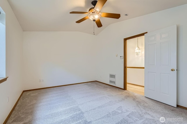 carpeted spare room featuring visible vents, baseboards, and lofted ceiling