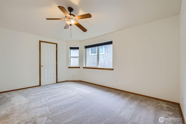 spare room with light carpet, a ceiling fan, and baseboards