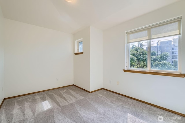 unfurnished room with baseboards and light colored carpet