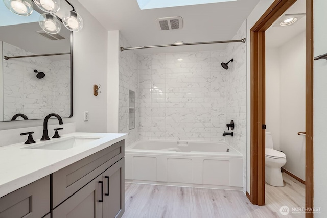 bathroom featuring visible vents, toilet, shower / bathing tub combination, a skylight, and vanity