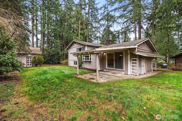 back of property with a patio, a lawn, and a chimney