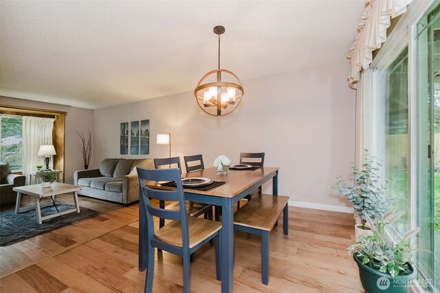 dining space with light wood-type flooring, baseboards, and a chandelier