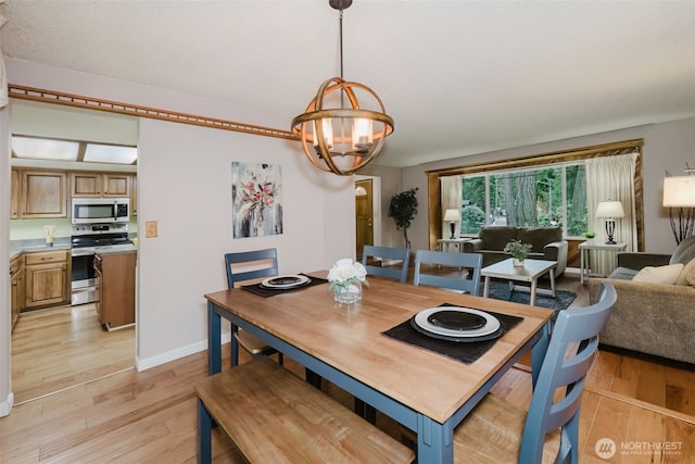 dining room with baseboards, an inviting chandelier, and light wood-style flooring