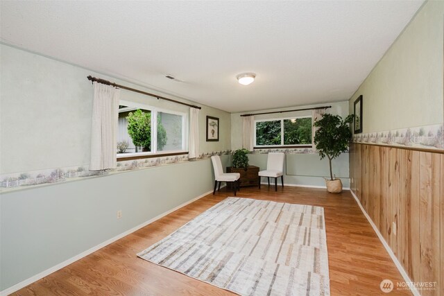 unfurnished room featuring light wood-type flooring, plenty of natural light, and baseboards