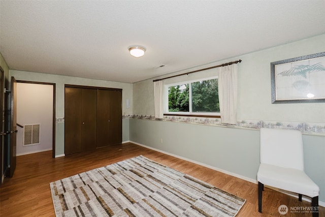 unfurnished bedroom featuring visible vents, baseboards, a closet, and wood finished floors