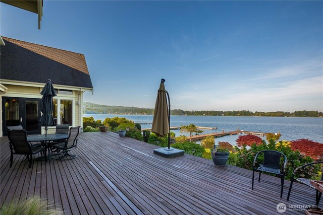 wooden terrace featuring outdoor dining area and a water view