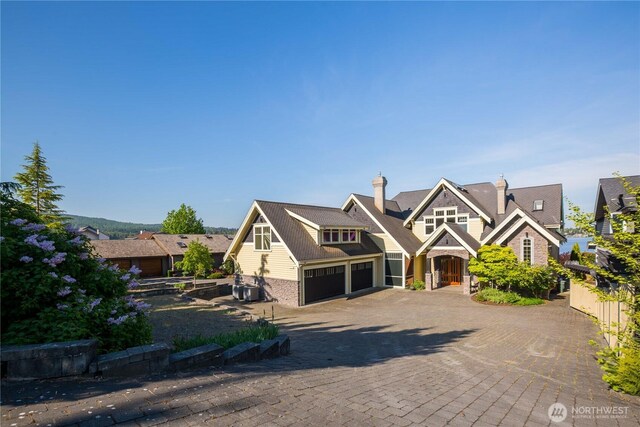 view of front of home with decorative driveway, fence, cooling unit, and an attached garage