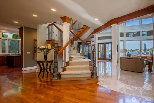 staircase with wood finished floors, recessed lighting, french doors, baseboards, and ornate columns