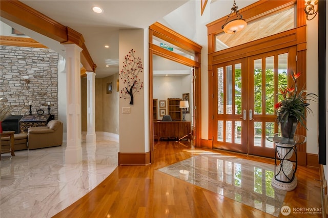 foyer featuring decorative columns, french doors, marble finish floor, and baseboards