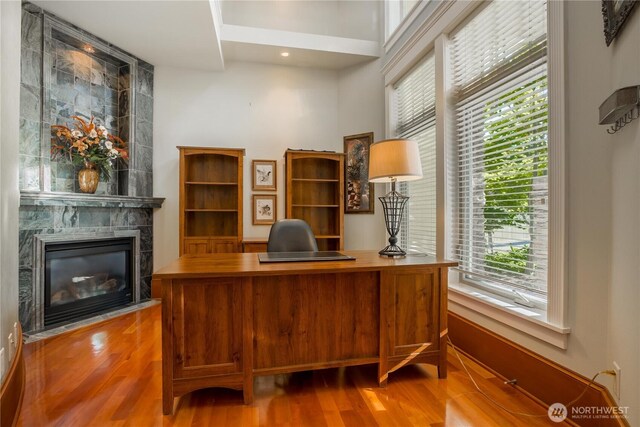 home office with wood finished floors and a tile fireplace